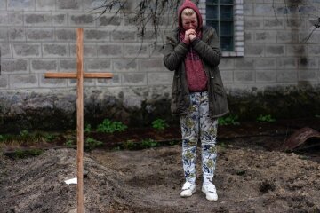 женщина плачет над могилой во дворе